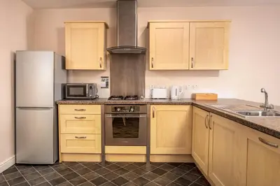 a kitchen with wooden cabinets and a stainless steel refrigerator at Elliot Suite No9 - Donnini Apartments in Ayr