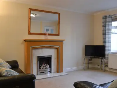 a living room with a fireplace and a mirror at Alan's Cottage in Cockermouth