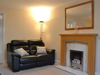 a black leather chair in a living room with a fireplace at Alan's Cottage in Cockermouth