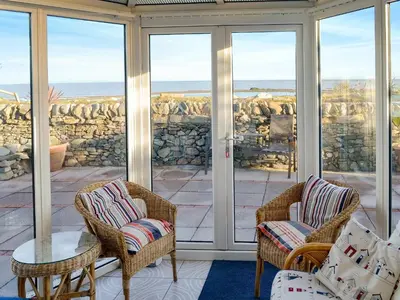 a screened in porch with two chairs and a table at Wavecrest in Mainsriddle