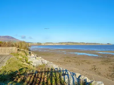 a beach with a fence and the water at Wavecrest in Mainsriddle