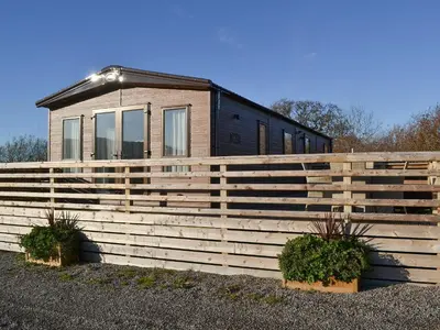 a house with a wooden fence and two plants at Watches - Uk13544 in Bassenthwaite