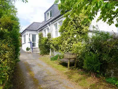 a bench sitting in front of a white house at Rowan Cottage in New Galloway
