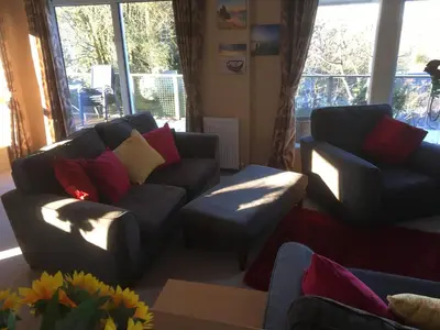 a living room with a couch and a chair at STUNNING LODGE - HOME FROM HOME Kippford, Dalbeattie in Dalbeattie