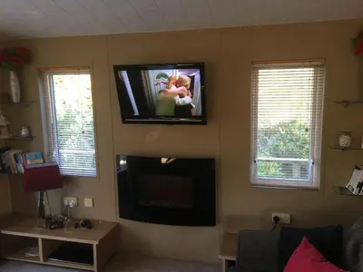 a living room with a flat screen tv on the wall at STUNNING LODGE - HOME FROM HOME Kippford, Dalbeattie in Dalbeattie