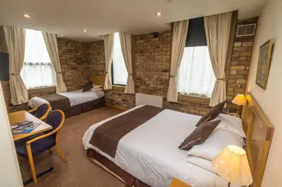 a hotel room with two beds and a table and chairs at The Sleepwell Inn in Workington