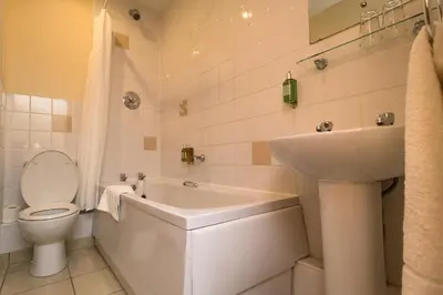 a white bathroom with a toilet and a sink at The Sleepwell Inn in Workington