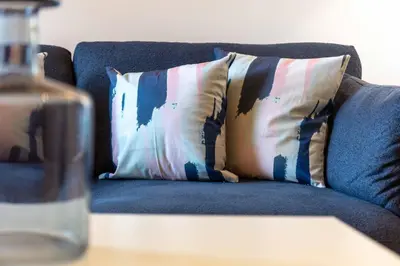 a blue couch with a pillow on a table with a water bottle at Elliot Suite No 1 - Donnini Apartments in Ayr