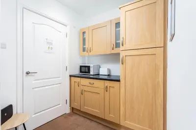 a small kitchen with wooden cabinets and a door at Elliot Suite No 1 - Donnini Apartments in Ayr