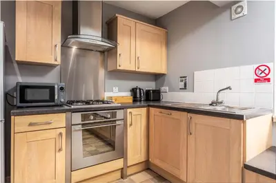 a kitchen with wooden cabinets and a stove top oven at Elliot Suite No3 - Donnini Apartments in Ayr
