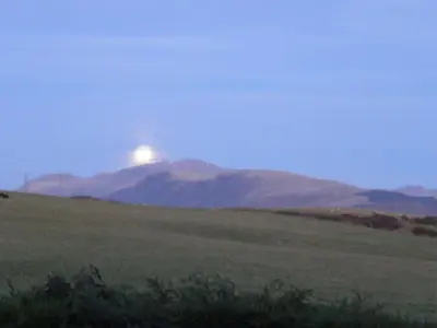 a view of a field with the sun rising over mountains at DAIRY MAIDS COTTAGE in Seascale