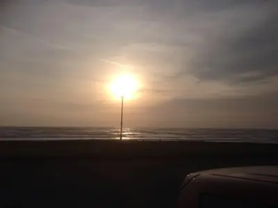 a light pole on the beach with the sun at DAIRY MAIDS COTTAGE in Seascale
