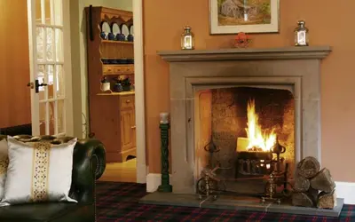 a living room with a fireplace with a fire in it at Find Me Out Holiday Cottage in Dalmellington
