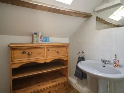 a bathroom with a sink and a wooden cabinet at Mousehole Cottage in Carlisle