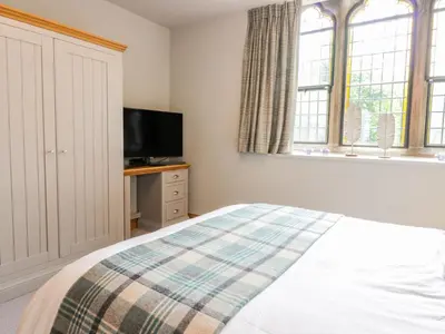 a bedroom with a bed and a flat screen tv at Apartment 1 St Mary's Church in Moffat