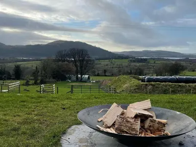 a pile of wood on a table in a field at The Huts at Highside Farm in Keswick