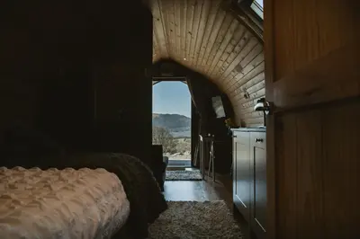 a bedroom with a bed and an open doorway at The Huts at Highside Farm in Keswick