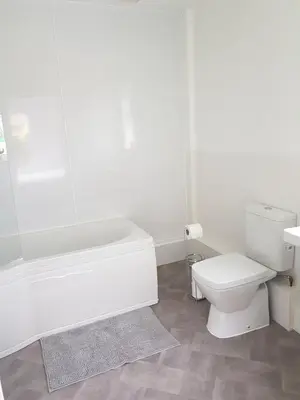 a bathroom with a white tub and a toilet at Cleughfoot House in Moffat