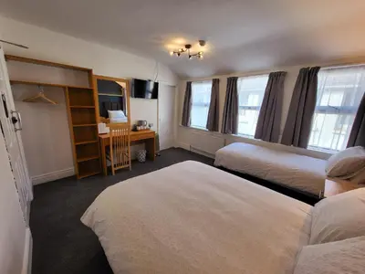 a hotel room with two beds and a desk at At Caledonia in Douglas