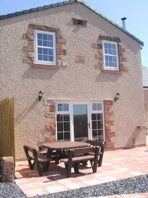 a wooden picnic table in front of a building at THE OLD FARMHOUSE in Holmrook