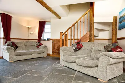 a living room with two couches and a staircase at THE OLD FARMHOUSE in Holmrook