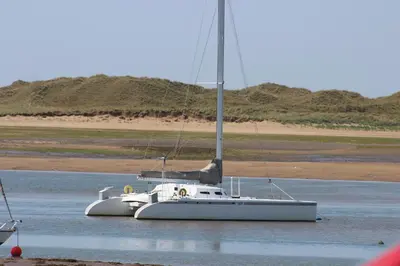 a sailboat sitting in the water on a beach at THE OLD FARMHOUSE in Holmrook