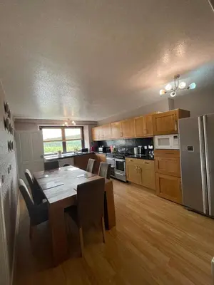 a kitchen with a dining table and a kitchen with a refrigerator at Carminnows Holiday Cottage in Carsphairn
