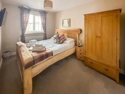 a bedroom with a bed and a wooden cabinet at West Fells Cottage in Arlecdon