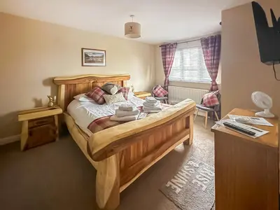 a bedroom with a wooden bed and a desk at West Fells Cottage in Arlecdon