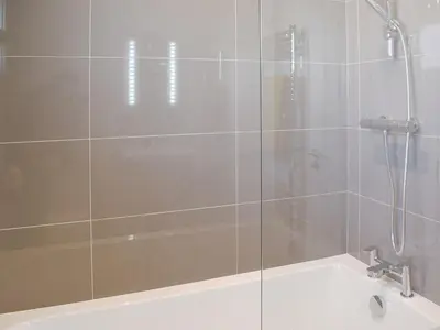 a shower with a glass door next to a bath tub at Willow Lodge - Uk13637 in Creetown
