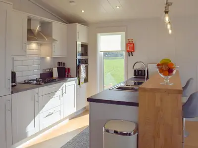 a kitchen with white cabinets and a counter with a bowl of fruit at Willow Lodge - Uk13637 in Creetown