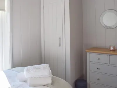 a bedroom with a bed and a dresser with towels at Willow Lodge - Uk13637 in Creetown