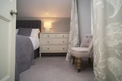 a bedroom with a bed and a chair and a dresser at Bakers Rest ideal for 2 families centrally located in Grasmere with walks from the door in Grasmere
