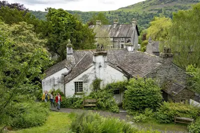 people walking in front of an old house at Bakers Retreat spacious 1st floor apartment centrally located in Grasmere in Ambleside