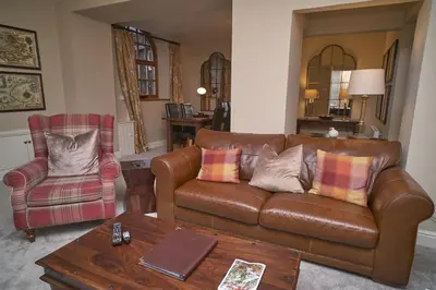 a living room with a leather couch and a chair at Old Bakers Cottage ground floor apartment centrally located in Grasmere with patio area in Grasmere