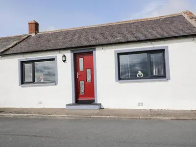 a white house with a red door on a street at 2 Whiterow in Powfoot