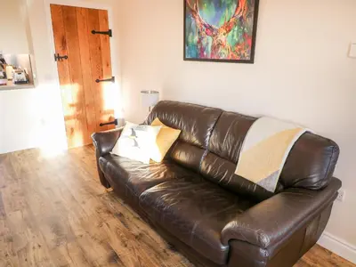 a brown leather couch sitting in a living room at Glebe Cottage in Dumfries