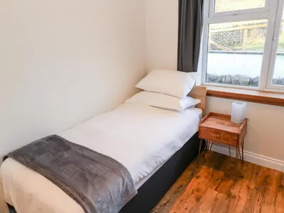 a small bed in a room with a window at Glebe Cottage in Dumfries