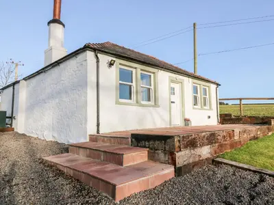 a small white house with stairs in front of it at Glebe Cottage in Dumfries