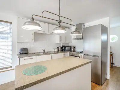 a kitchen with white cabinets and a stainless steel refrigerator at Coney Garth Barn in Beckermet