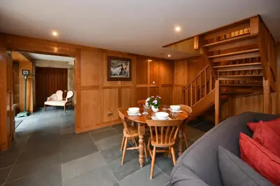 a living room with a table and a staircase at Cloncaird Castle Estate Cottages in Maybole