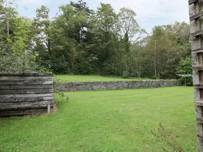 a field with a stone wall and trees at Cloncaird Castle Estate Cottages in Maybole