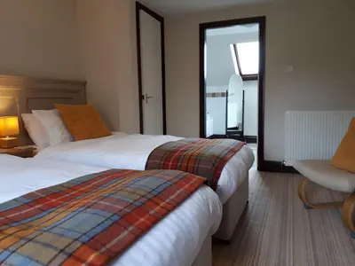 a hotel room with two beds and a chair at Corsewall Arms Guest House in Stranraer