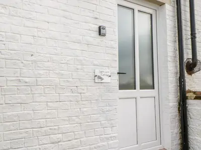 a white brick wall with a white door at Tight Lyne Cottage in Carlisle