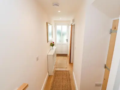 a hallway with white walls and a door with a window at Tight Lyne Cottage in Carlisle