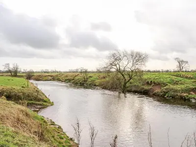 a river in the middle of a field at Tight Lyne Cottage in Carlisle