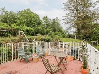 a patio with chairs and a table and a fence at The Barn in Dalbeattie