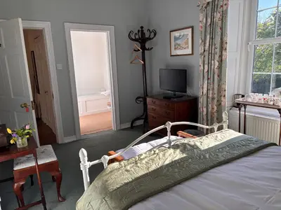 a bedroom with a bed and a tv and a window at Applegarth House in Lockerbie