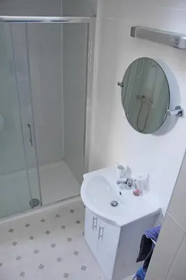 a bathroom with a shower and a sink and a mirror at Ashfield Guesthouse in Douglas