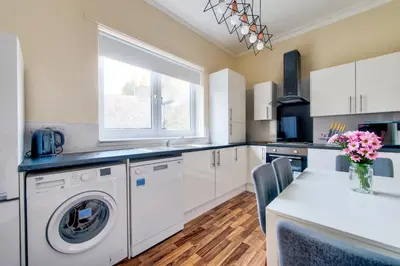 a kitchen with a washing machine and a table with chairs at Oaktree Appartment Moffat in Moffat